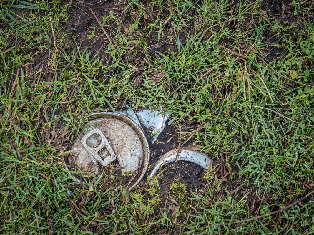 Discarded soft drink can trodden into a walking path. Rubbish, Australia.